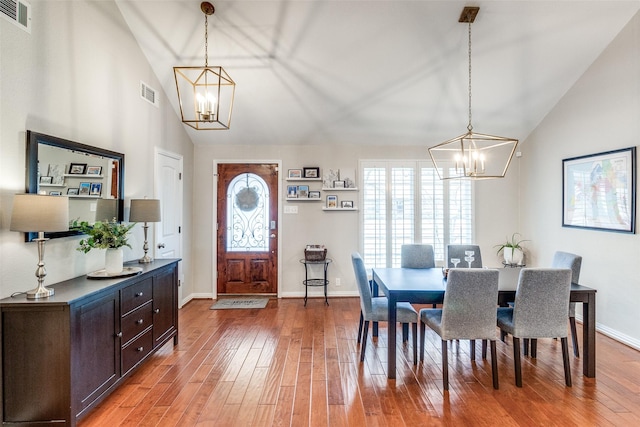 dining space with visible vents, a notable chandelier, and wood finished floors