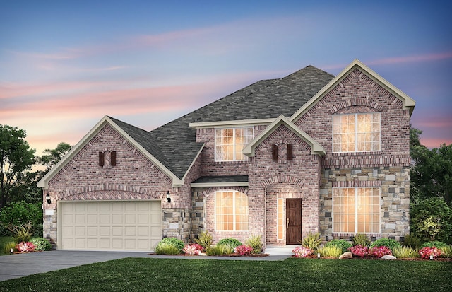 french country inspired facade with driveway, a garage, a shingled roof, a front lawn, and brick siding