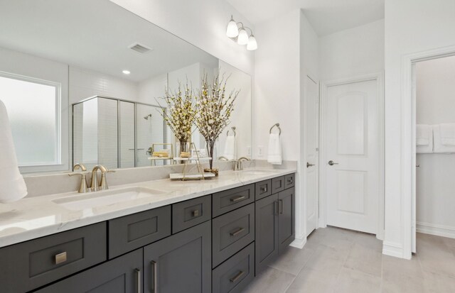 full bath featuring double vanity, a shower stall, visible vents, and a sink