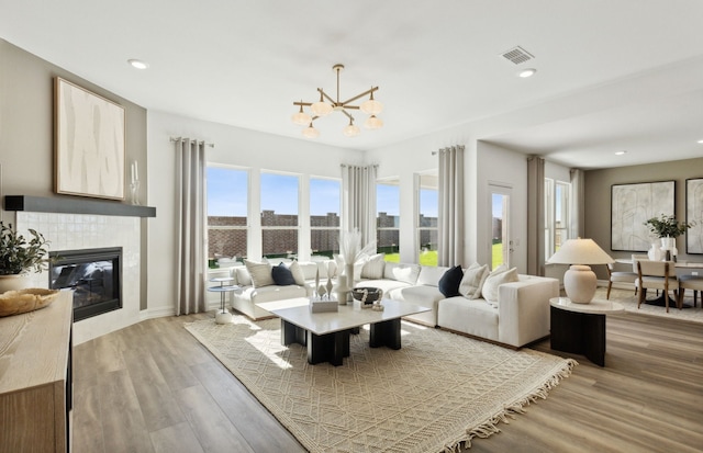 living room featuring recessed lighting, a fireplace, wood finished floors, visible vents, and an inviting chandelier