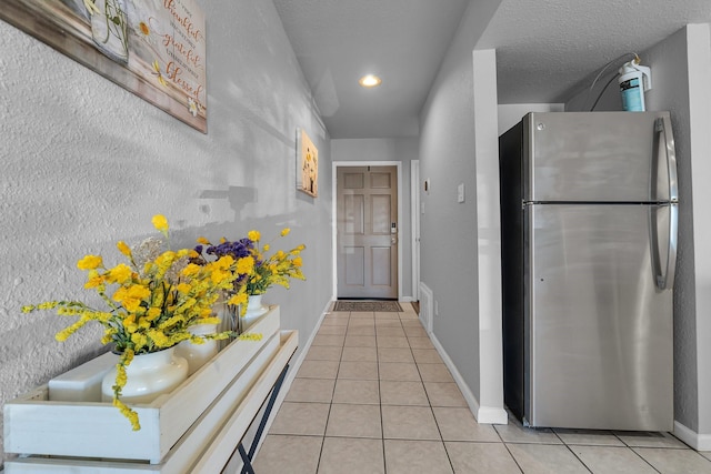 hall featuring light tile patterned floors, baseboards, a textured ceiling, and recessed lighting