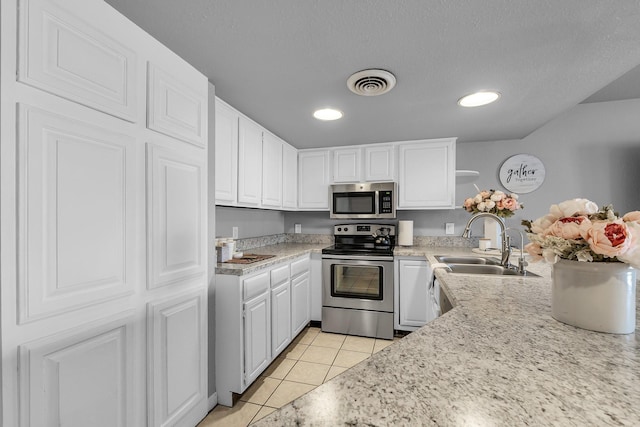 kitchen with light tile patterned floors, stainless steel appliances, light countertops, visible vents, and white cabinets