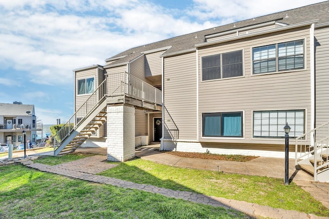 rear view of house featuring stairway and a lawn