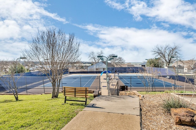 view of sport court with a lawn and fence