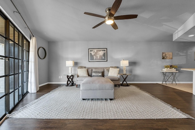 living room with a ceiling fan, baseboards, and wood finished floors