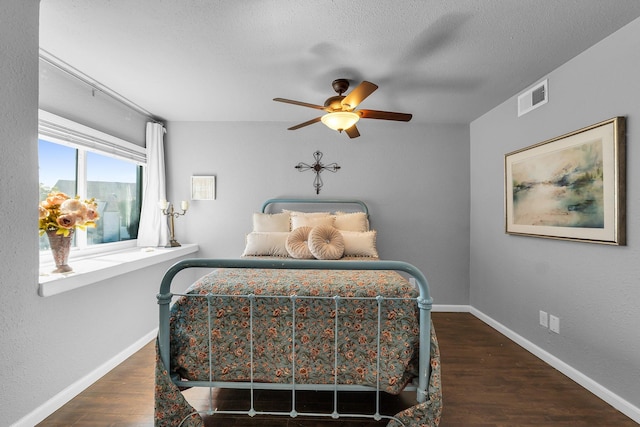 bedroom with baseboards, visible vents, a ceiling fan, wood finished floors, and a textured ceiling