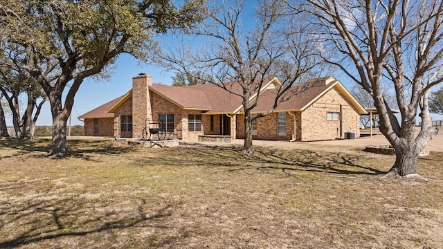 ranch-style home with brick siding, a chimney, and a front lawn