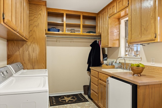 laundry room with cabinet space, baseboards, washer and dryer, and a sink