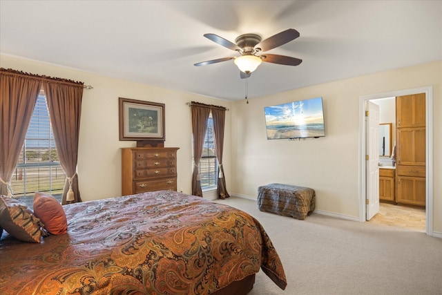 bedroom featuring light carpet, ceiling fan, connected bathroom, and baseboards