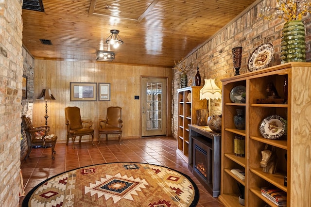 sitting room with brick wall, tile patterned flooring, and wood ceiling