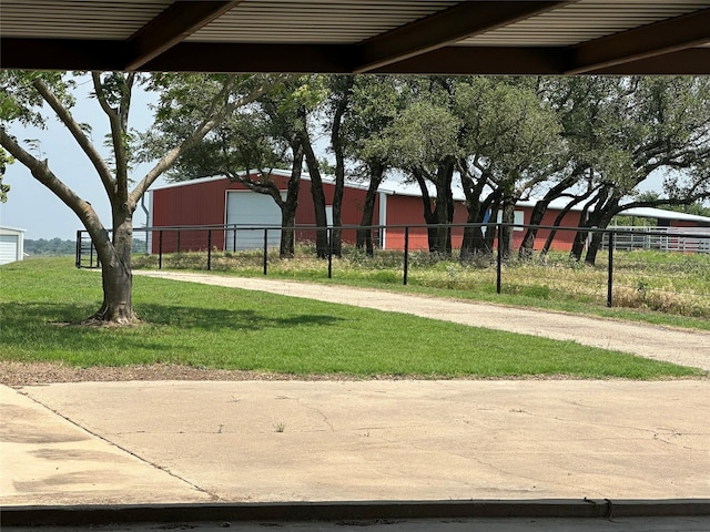 view of yard featuring fence, driveway, and an outdoor structure