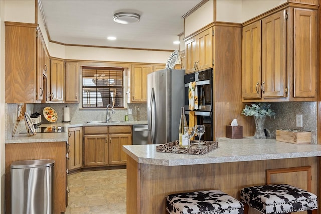 kitchen featuring a peninsula, appliances with stainless steel finishes, light countertops, and a sink