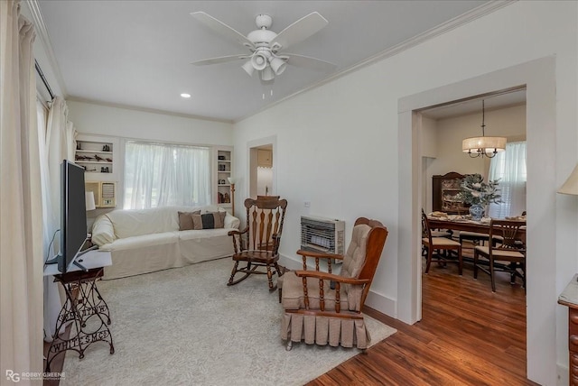 sitting room featuring a healthy amount of sunlight, heating unit, crown molding, and wood finished floors