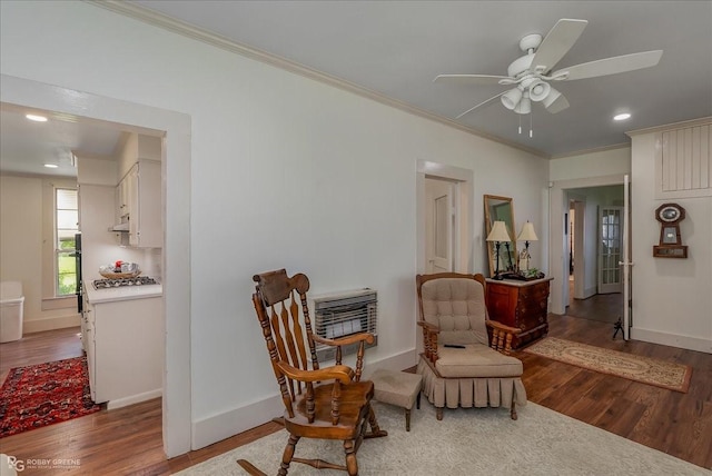 sitting room with ornamental molding, a ceiling fan, baseboards, and wood finished floors