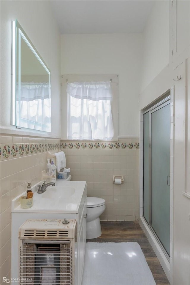 full bathroom with heating unit, toilet, wainscoting, a shower stall, and vanity