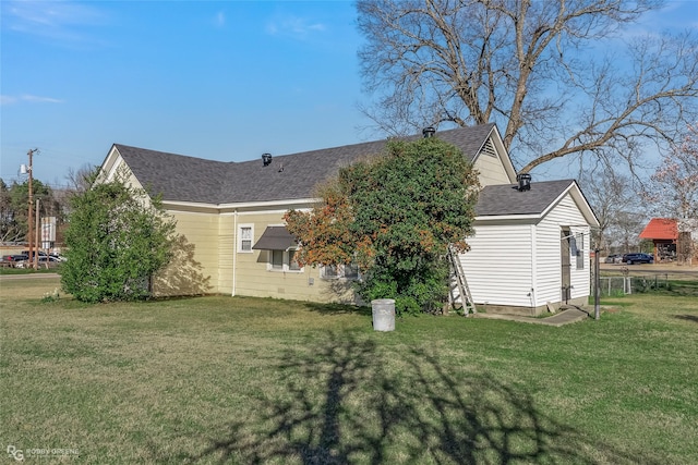 back of house with a shingled roof and a lawn