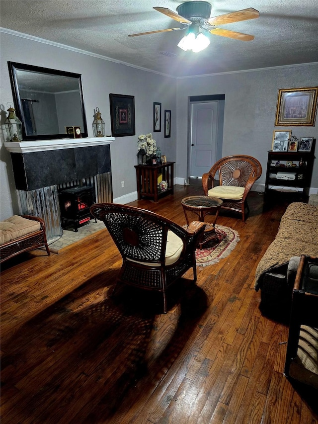 living area featuring crown molding, wood-type flooring, a ceiling fan, a textured ceiling, and baseboards