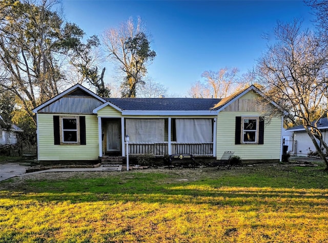 view of front of home with roof with shingles and a front yard