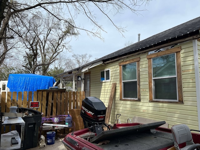 view of property exterior with fence and roof with shingles