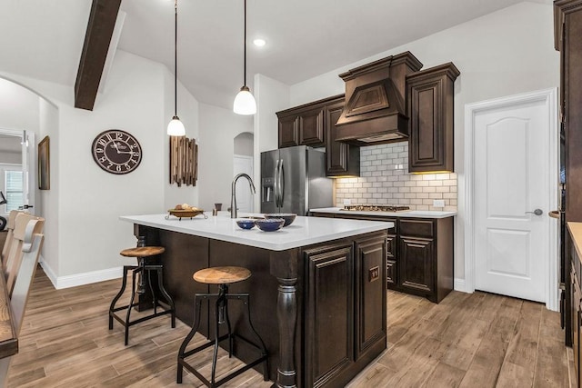 kitchen featuring custom range hood, arched walkways, stainless steel refrigerator with ice dispenser, and light wood finished floors