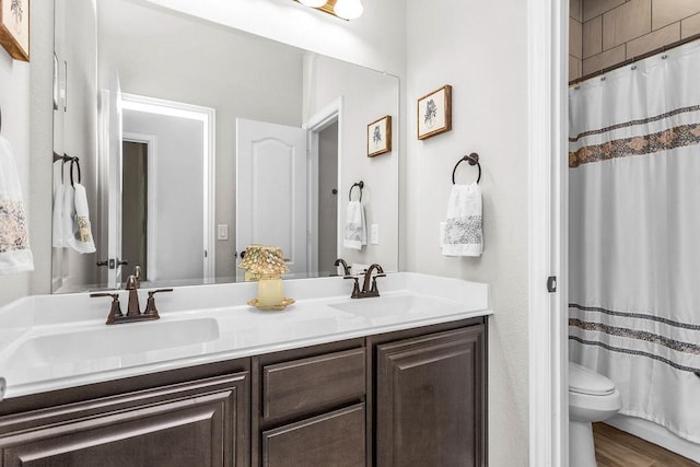 bathroom featuring curtained shower, double vanity, toilet, and a sink