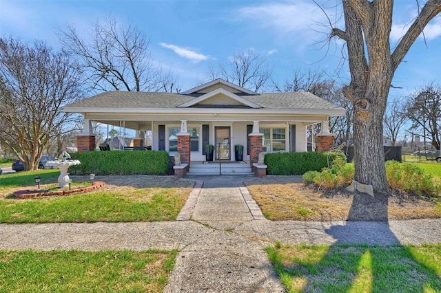 view of front of house featuring covered porch, brick siding, and roof with shingles