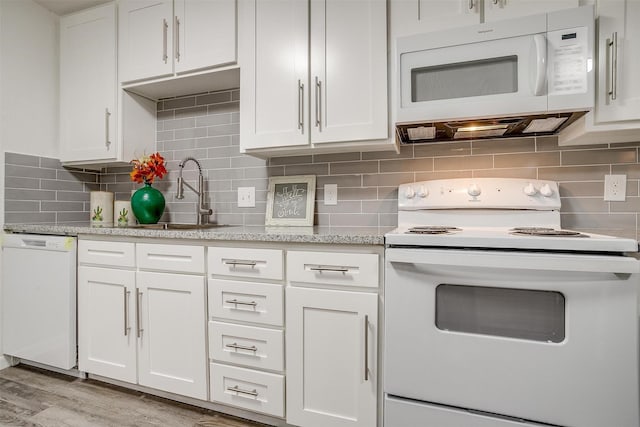 kitchen featuring white appliances, a sink, white cabinets, light wood-type flooring, and tasteful backsplash