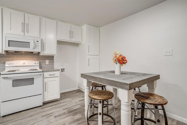 kitchen with white cabinets, white appliances, light wood-type flooring, and decorative backsplash