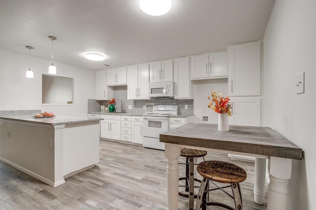 kitchen with white appliances, decorative backsplash, light wood-style flooring, decorative light fixtures, and white cabinetry