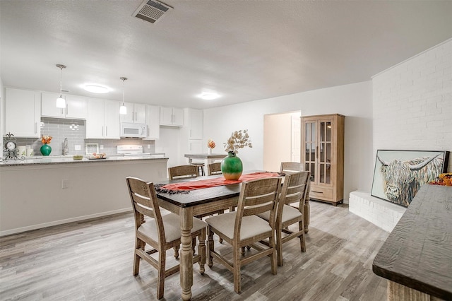 dining area featuring visible vents, a fireplace, and light wood finished floors