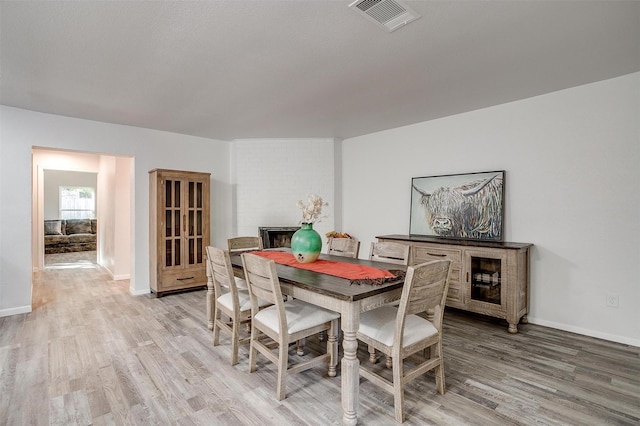 dining space with baseboards, visible vents, and light wood-style floors