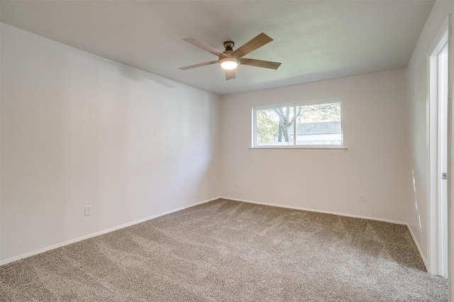 empty room with carpet flooring, a ceiling fan, and baseboards