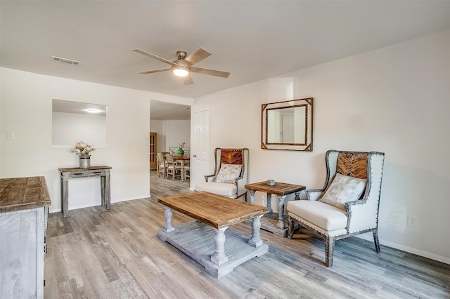 sitting room featuring a ceiling fan, light wood-style flooring, visible vents, and baseboards