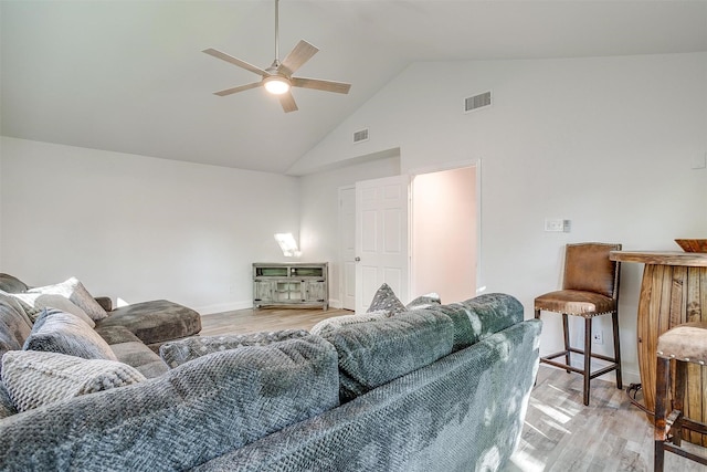 living room with light wood finished floors, visible vents, and high vaulted ceiling