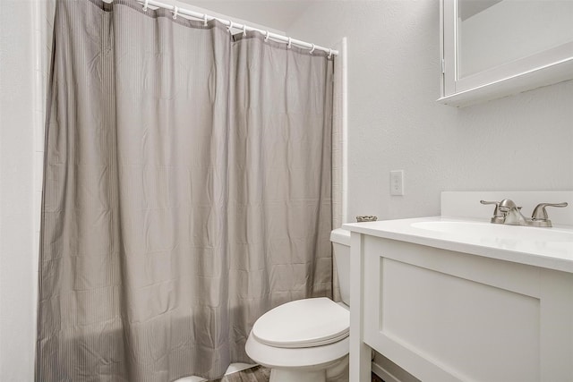 full bathroom featuring a textured wall, vanity, toilet, and a shower with curtain