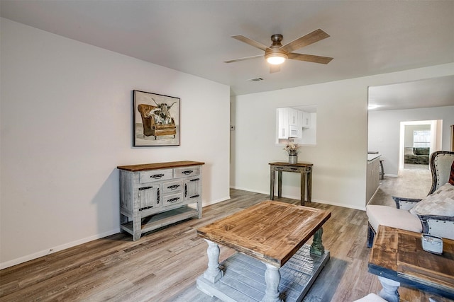 living area with ceiling fan, wood finished floors, visible vents, and baseboards