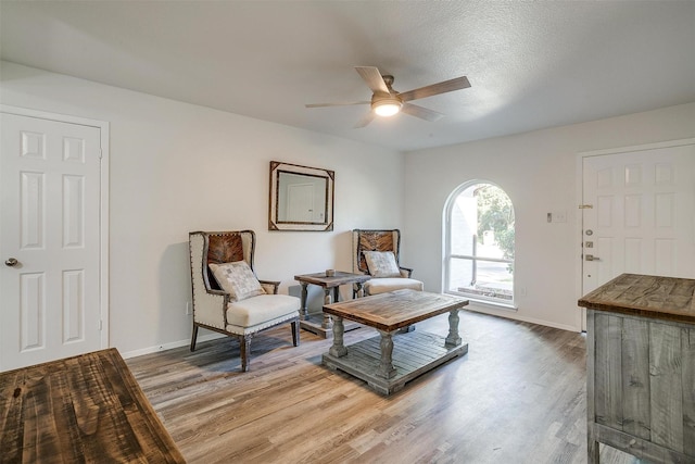 sitting room with light wood-type flooring, a ceiling fan, and baseboards