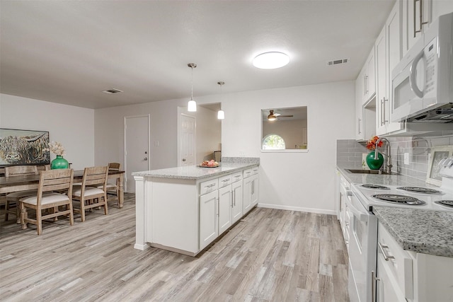 kitchen with white appliances, visible vents, a sink, and a peninsula