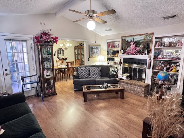 living room featuring lofted ceiling with beams, a textured ceiling, visible vents, and wood finished floors