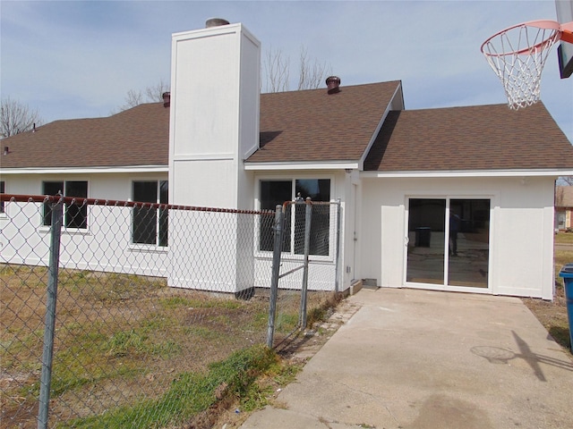 rear view of house with a shingled roof, a chimney, and fence