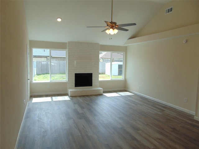 unfurnished living room with vaulted ceiling, a wealth of natural light, dark wood-style floors, and visible vents