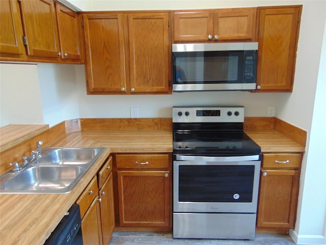 kitchen featuring stainless steel appliances, butcher block counters, brown cabinetry, and a sink