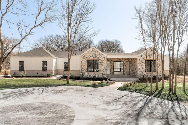 view of front of home featuring covered porch, stone siding, brick siding, and a front yard