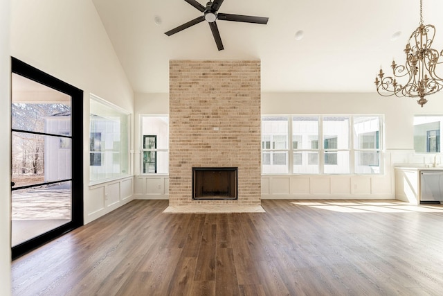 unfurnished living room featuring a fireplace, lofted ceiling, a decorative wall, wood finished floors, and ceiling fan with notable chandelier