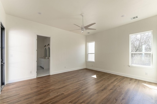 unfurnished room with baseboards, visible vents, ceiling fan, and dark wood-style flooring