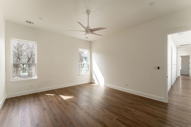 empty room featuring ceiling fan, dark wood-type flooring, visible vents, and baseboards