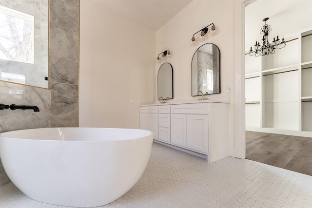 bathroom featuring a freestanding tub, a sink, an inviting chandelier, and double vanity