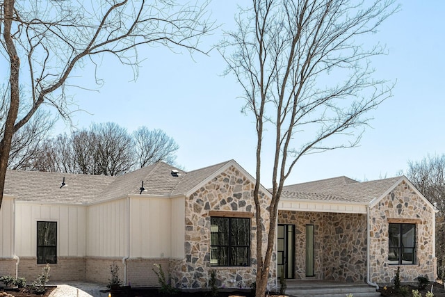 exterior space featuring board and batten siding and roof with shingles