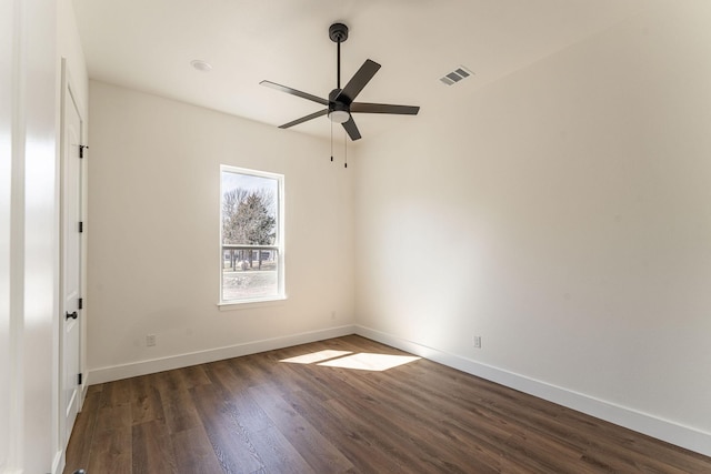 spare room with a ceiling fan, dark wood-style flooring, visible vents, and baseboards