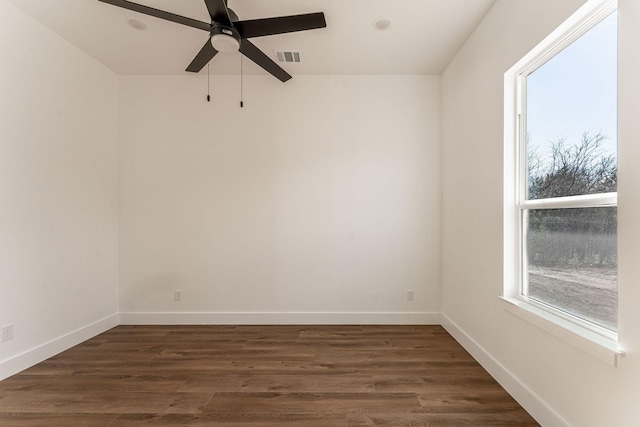 spare room featuring ceiling fan, visible vents, baseboards, and dark wood finished floors